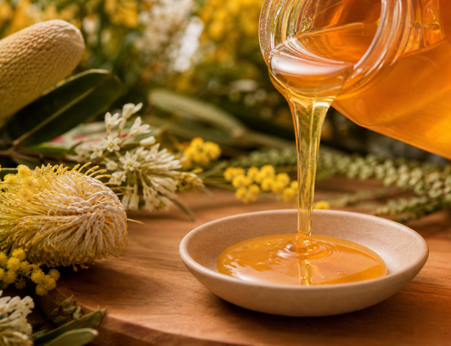 Golden raw honey being poured with Australian native wildflowers - honey delivery Gold Coast