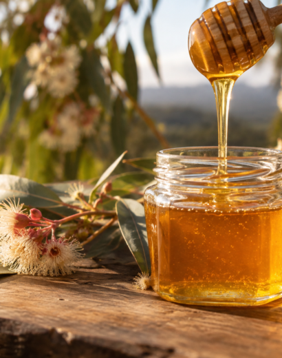 Golden raw honey being poured into a jar with native Australian gum blossoms, Gold Coast honey