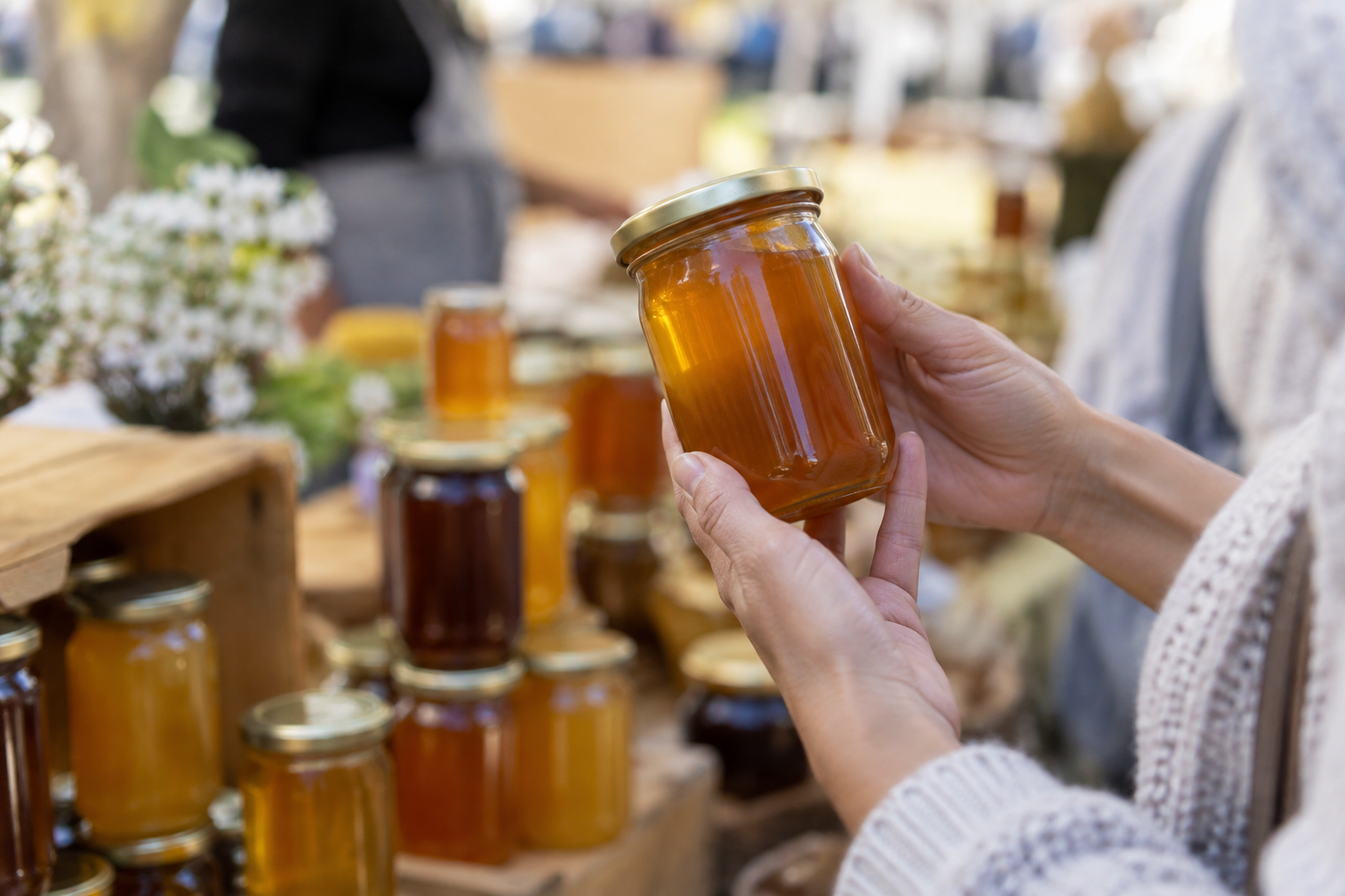 Shopper holding a jar of raw honey at a pop-up market stall